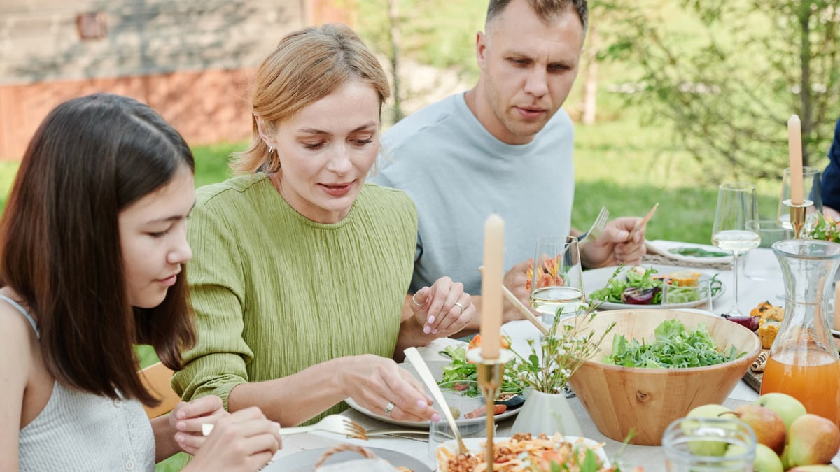 A family shares a meal outdoors, enjoying fresh and vibrant salads.