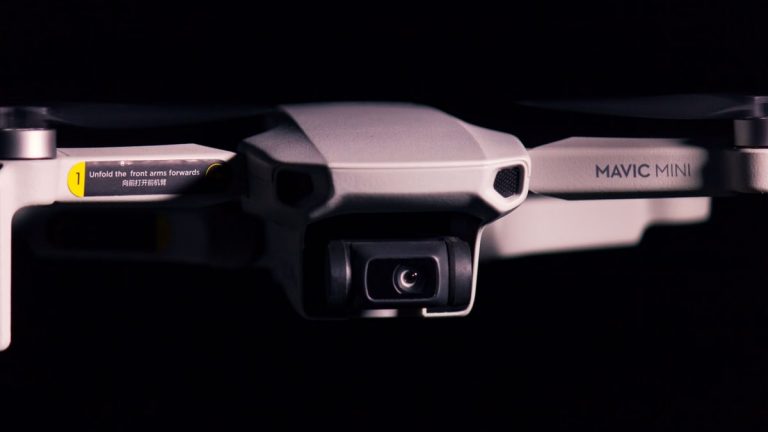 Detailed shot of a Mavic Mini drone showcasing its camera and design against a black background.